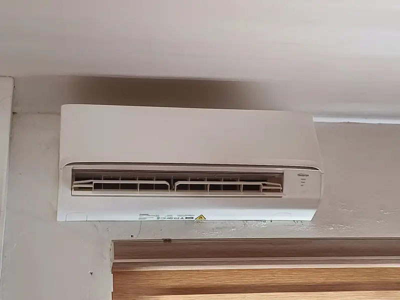 Minisplit blanco instalado en la parte alta de una pared